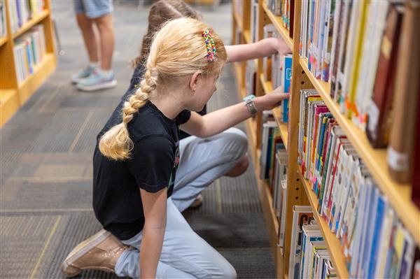girl picking book off shelf